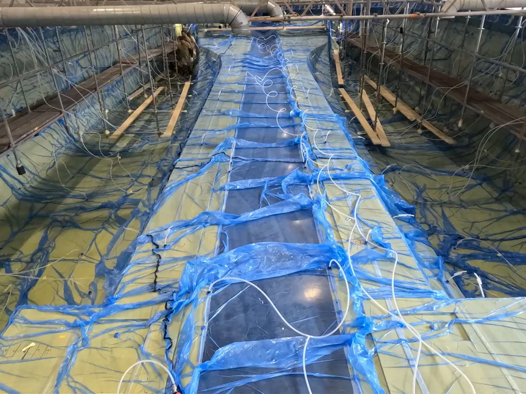 Vacuum infusion process of the LANIAKEA hull in progress at Latitude Yachts shipyard, showing composite layers and resin flow setup inside the mold